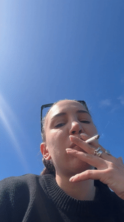 Woman smoking cigarette observed in Étretat, France