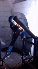 Worker welds metal pipe in indoor facility