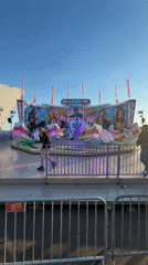 Fairground rides operate as visitors enjoy outdoor amusement park