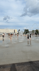 Kids play in fountain spray at a wet Izhevsk plaza