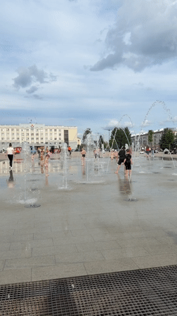 Kids play in fountain spray at a wet Izhevsk plaza