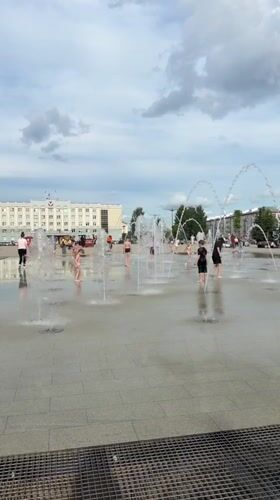 Kids play in fountain spray at a wet Izhevsk plaza