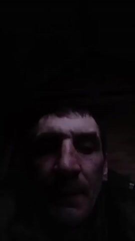 A person's face is visible in low light, obscuring details but showing a nose, mouth, and eyes. The background is entirely dark. The camera appears to be held close to the person's face.