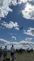 Small plane flies over sunny outdoor crowd event in Cheb