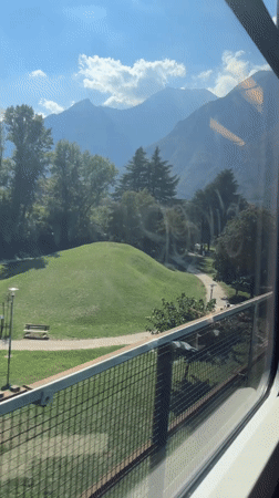 Train ride through Trento, Alps framing the view outside
