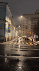 Nighttime snowfall documented on wet urban streets
