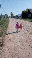 Two girls walk hand-in-hand on dirt road in Russia
