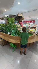 Child explores toy store with animatronic dinosaur in Kuta mall