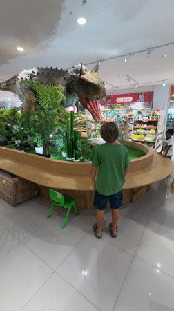 Child explores toy store with animatronic dinosaur in Kuta mall