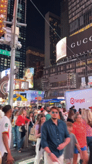 Late-night Midtown: Times Square crowds and rainbow-lit Empire State Building