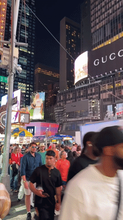 Late-night Midtown: Times Square crowds and rainbow-lit Empire State Building