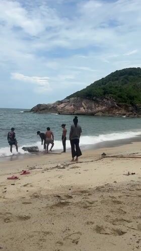 Group moves heavy barrel on Thai beach using planks