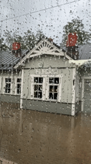 Rain-covered window frames a green station building in Riga