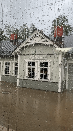 Rain-covered window frames a green station building in Riga