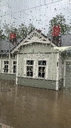 Rain-covered window frames a green station building in Riga