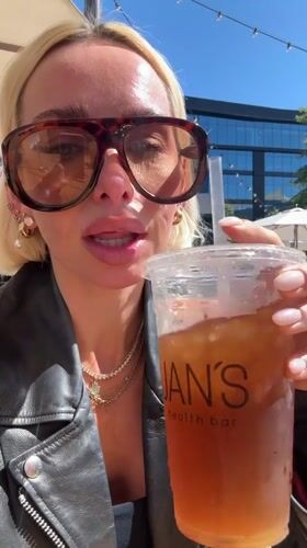 Woman enjoys iced drink at San Diego outdoor cafe