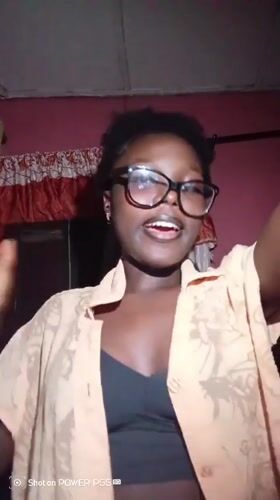 Selfie session in an Onitsha bedroom, orange shirt and glasses