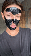 Woman applies black face mask during skincare routine