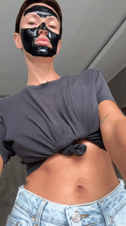 Woman applies black face mask during skincare routine