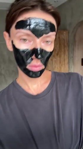 Woman applies black face mask during skincare routine