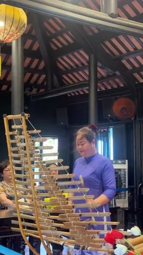 Woman plays traditional Vietnamese bamboo xylophone in Nha Trang