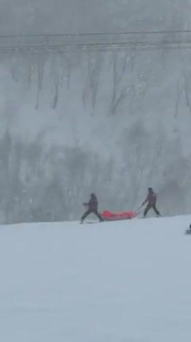 Skiers transport person on sled in Kutchan snow