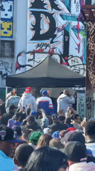 Large crowd gathers on New York street amid muraled buildings