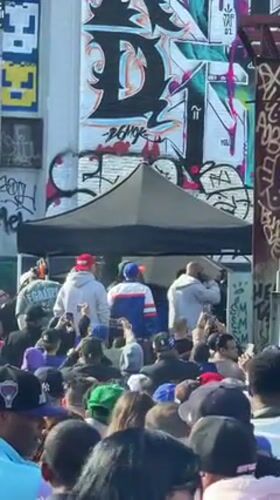 Large crowd gathers on New York street amid muraled buildings