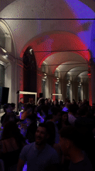 Crowd gathers in illuminated Milan courtyard during evening event