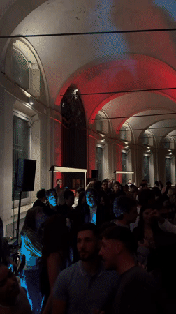 Crowd gathers in illuminated Milan courtyard during evening event