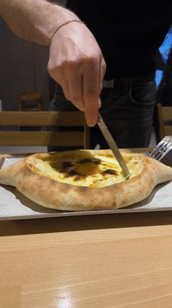 Man enjoys Georgian khachapuri dish at Barcelona restaurant