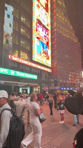 Times Square buzzes at night under glowing billboard light