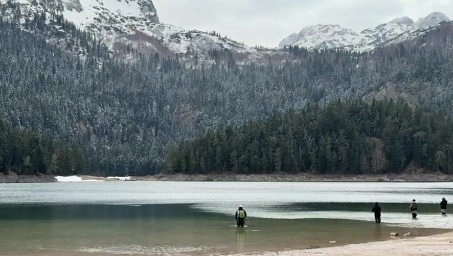 Person stands in calm lake waters in Montenegro