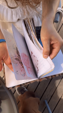 Person reviews art-filled notebook outdoors in Fethiye, Turkey