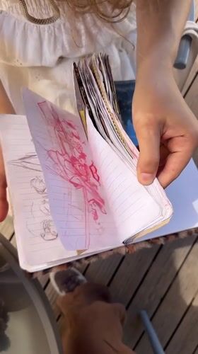 Person reviews art-filled notebook outdoors in Fethiye, Turkey