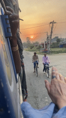 Passengers hang from moving blue vehicle in Nepal