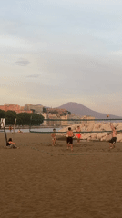 Young men play beach volleyball in Naples