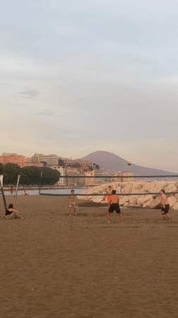 Young men play beach volleyball in Naples
