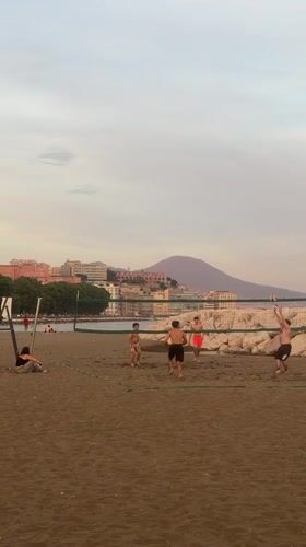 Young men play beach volleyball in Naples