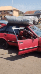 Woman exits red car with roof bags, trunk open