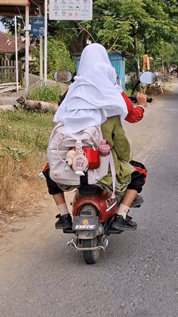 Red motorcycle duo with pink backpack cruising through Lhokseumawe