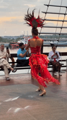 Traditional dancers perform in red costumes on Denpasar deck