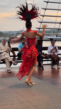 Traditional dancers perform in red costumes on Denpasar deck