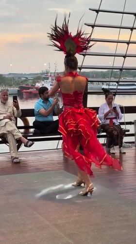 Traditional dancers perform in red costumes on Denpasar deck
