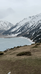Woman documents mountain lake scenery near Almaty, Kazakhstan