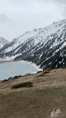 Woman documents mountain lake scenery near Almaty, Kazakhstan