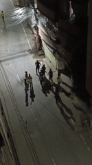 Nighttime street gathering in Dhaka with yellow-and-green flags