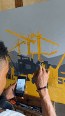 Artist paints construction cityscape using phone reference in Ado