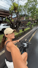 Woman cycles on wet road in Ubud, Indonesia