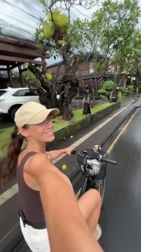 Woman cycles on wet road in Ubud, Indonesia